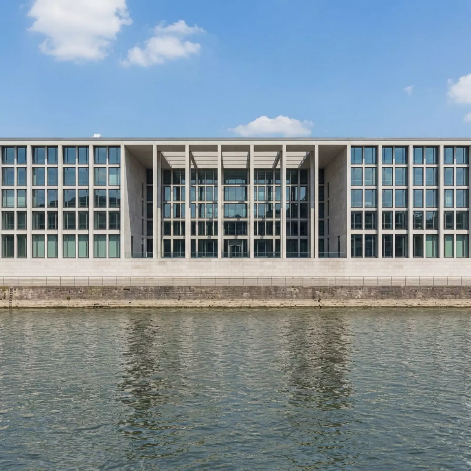 Das Bundeshaus in Bonn am Rheinufer, neutrale Uferlandschaft, keine Personen, keine Beschilderung.
